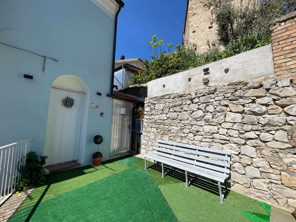 Panchina nel giardino davanti al muro in pietra della struttura