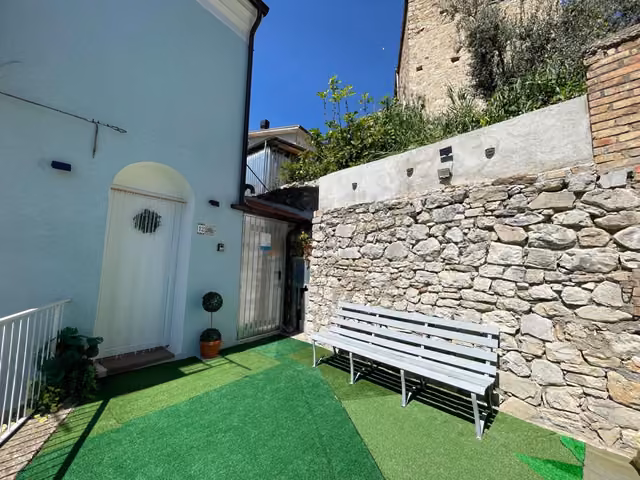 Panchina nel giardino davanti al muro in pietra della struttura